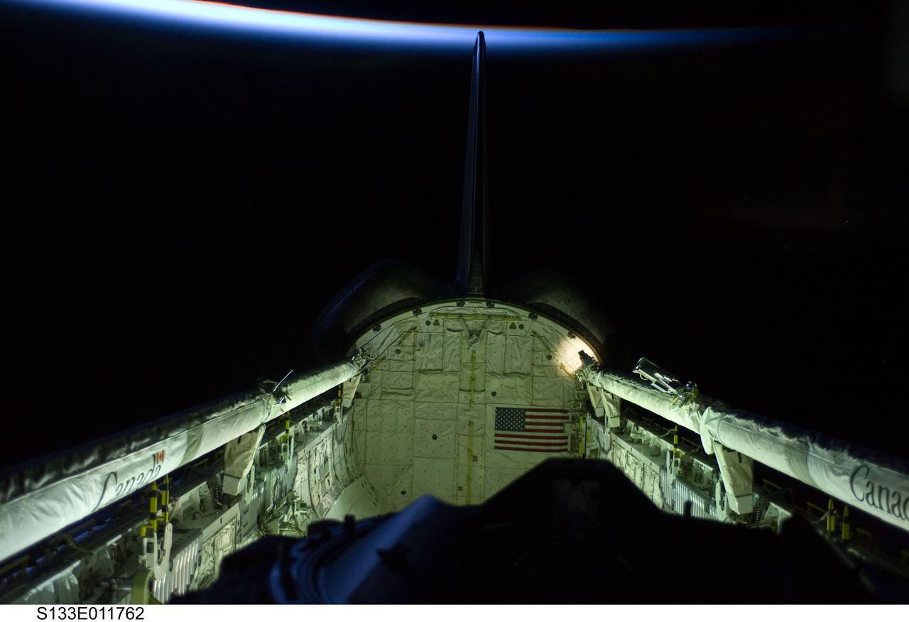 S133-E-011762 (7 March 2011) --- Space shuttle Discovery’s vertical stabilizer, orbital maneuvering system (OMS) pods, docking mechanism, remote manipulator system/orbiter boom sensor system (RMS/OBSS) and payload bay are featured in this image photographed by an STS-133 crew member on the shuttle during flight day 12 activities. The thin line of Earth’s atmosphere is at top. Photo credit: NASA or National Aeronautics and Space Administration
