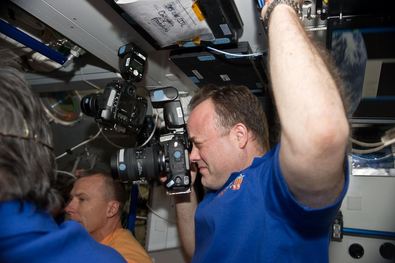 S134-E-007111 (18 May 2011) --- NASA astronaut Ron Garan, Expedition 27 flight engineer, uses a still camera in the Harmony node of the International Space Station shortly after space shuttle Endeavour and the space station docked in space and the hatches were opened. NASA astronaut Andrew Feustel, STS-134 mission specialist, is visible in the background. Photo credit: NASA