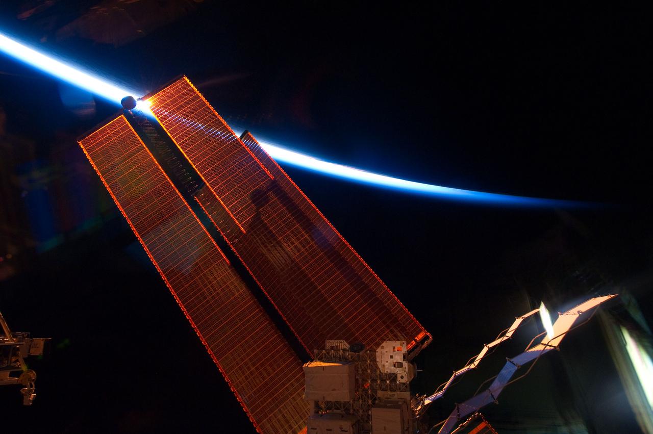 S134-E-007756 (20 May 2011) --- Intersecting the thin line of Earth’s atmosphere, International Space Station solar array wings are featured in this image photographed by an STS-134 crew member while space shuttle Endeavour remains docked with the station. Photo credit: NASA