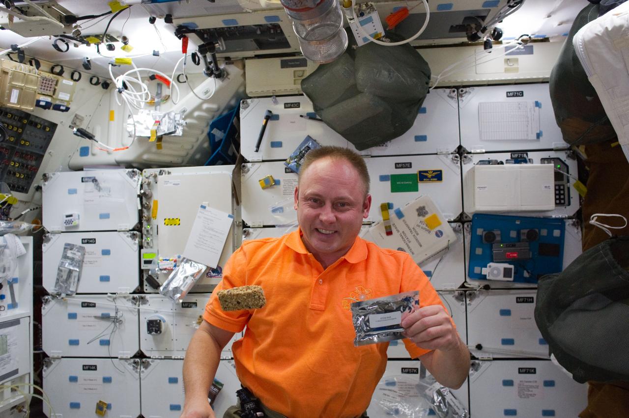 S134-E-009702 (28 May 2011) --- NASA astronaut Michael Fincke, STS-134 mission specialist, prepares to eat a snack on the middeck of space shuttle Endeavour while docked with the International Space Station during flight day 13. Photo credit: NASA