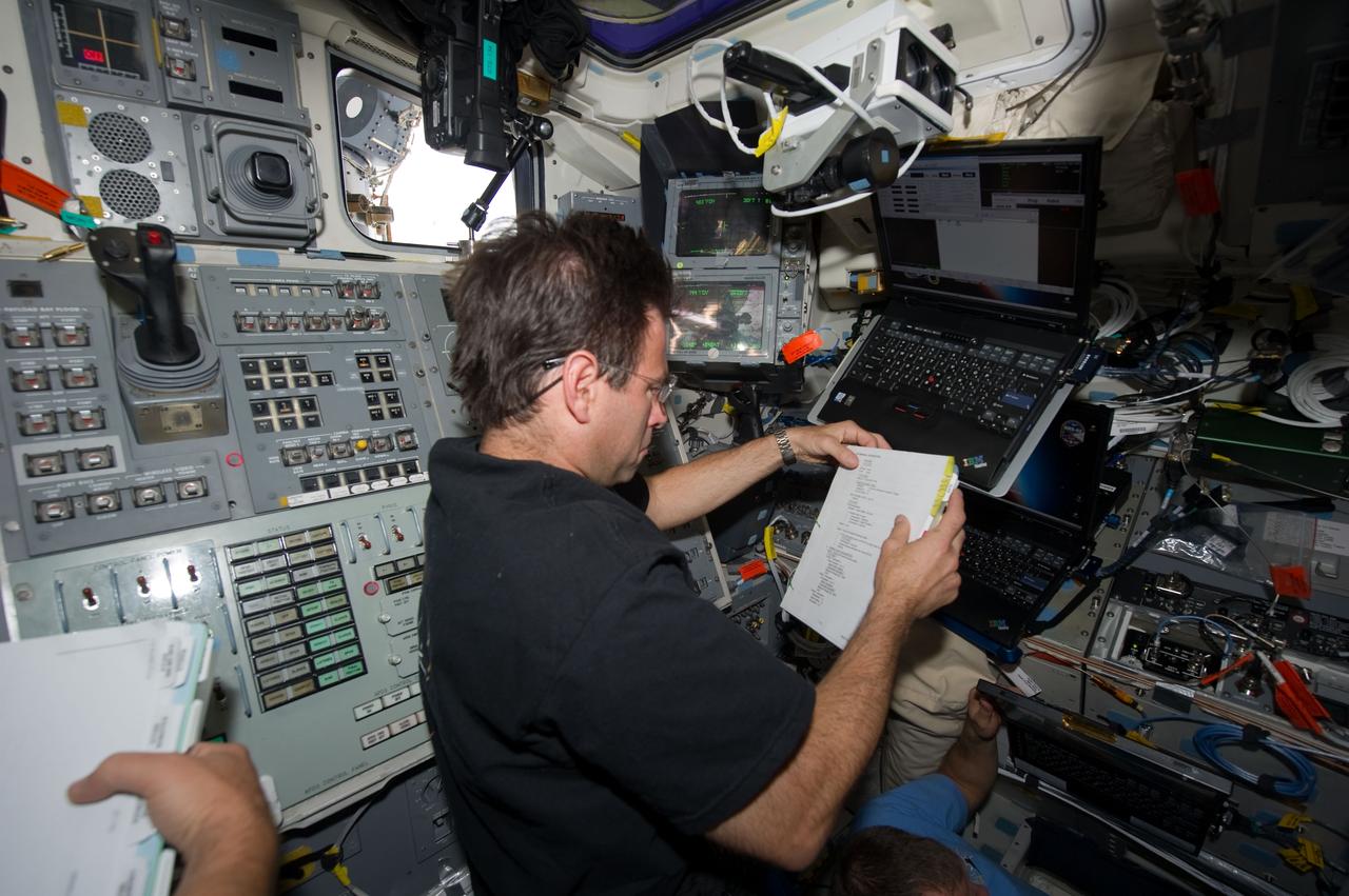 S134-E-010904 (30 May 2011) --- NASA astronaut Greg Chamitoff, STS-134 mission specialist, reads a procedures checklist while working on the aft flight deck of space shuttle Endeavour during flight day 15 activities. Photo credit: NASA