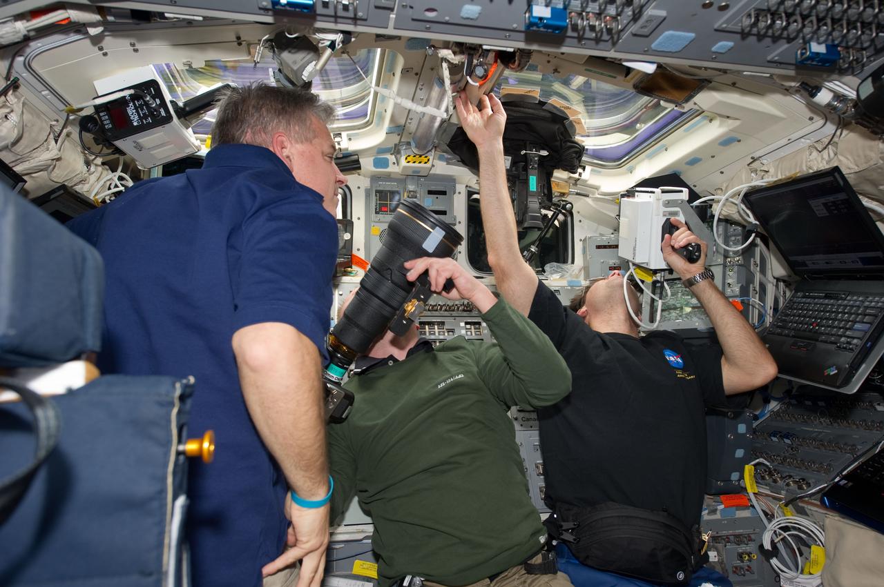 S134-E-010934 (30 May 2011) --- NASA astronauts Greg H. Johnson (left), STS-134 pilot; Michael Fincke (center) and Greg Chamitoff, both mission specialists, are busy on the aft flight deck of space shuttle Endeavour during undocking and fly-around operations with the International Space Station on flight day 15. Chamitoff is using a handheld laser ranging device -- designed to measure the range between two spacecraft -- through one of the overhead windows. Photo credit: NASA
