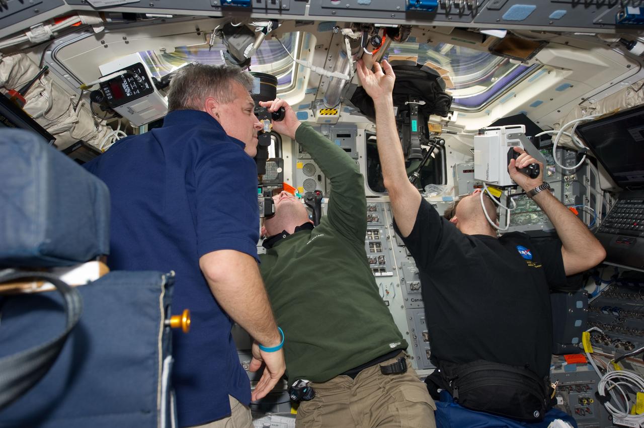 S134-E-010935 (30 May 2011) --- NASA astronauts Greg H. Johnson (left), STS-134 pilot; Michael Fincke (center) and Greg Chamitoff, both mission specialists, are busy on the aft flight deck of space shuttle Endeavour during undocking and fly-around operations with the International Space Station on flight day 15. Chamitoff is using a handheld laser ranging device -- designed to measure the range between two spacecraft -- through one of the overhead windows. Photo credit: NASA