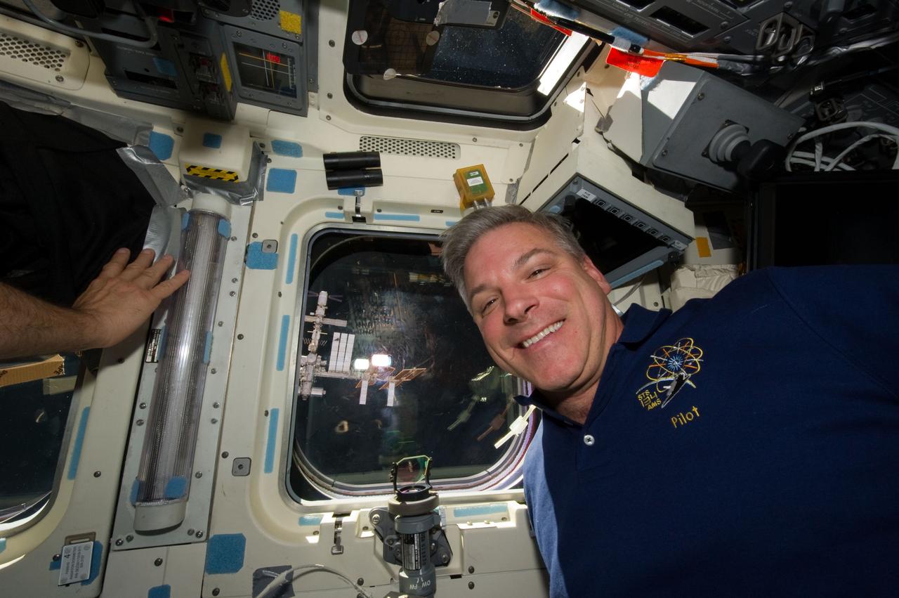 S134-E-010959 (30 May 2011) --- NASA astronaut Greg H. Johnson, STS-134 pilot, is pictured near an overhead window on the aft flight deck of space shuttle Endeavour after undocking with the International Space Station (visible through the window) on flight day 15. Photo credit: NASA