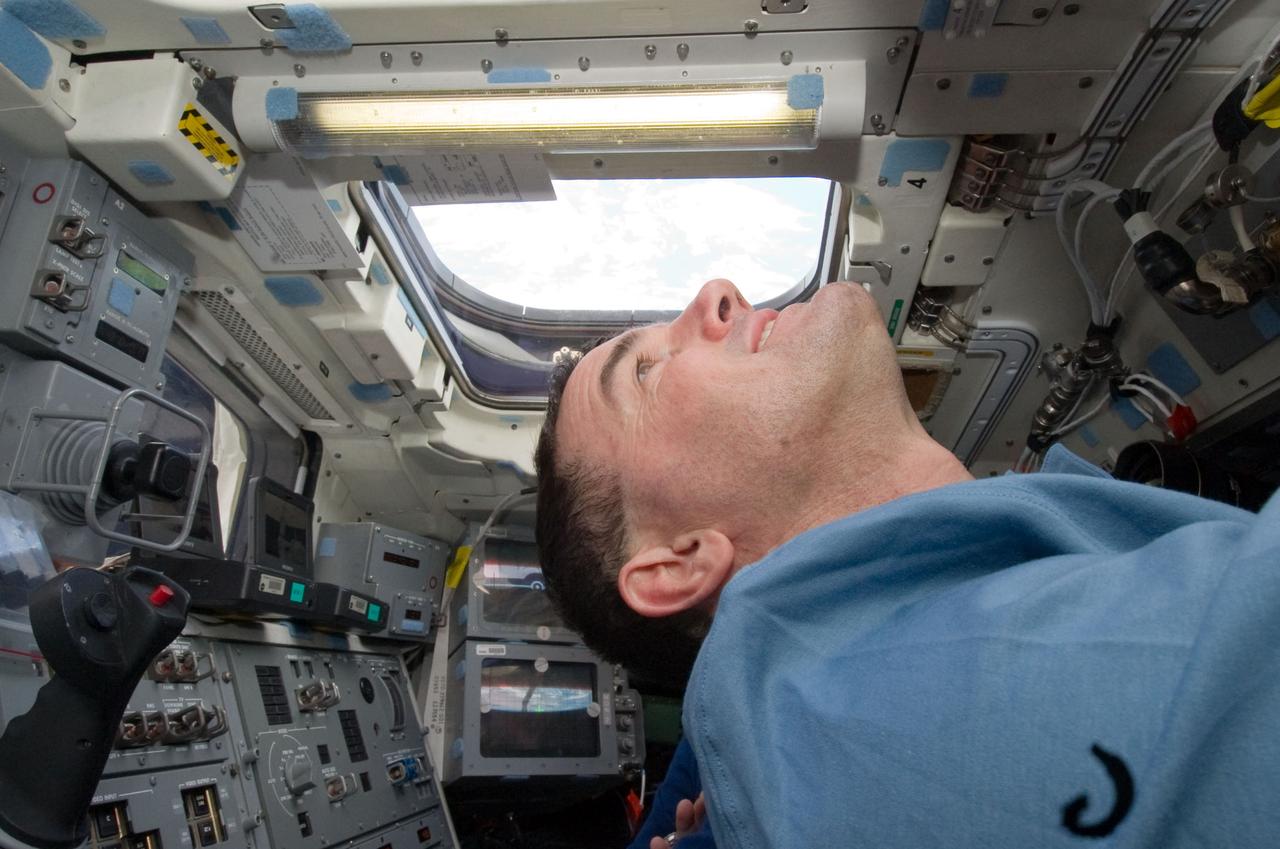 S135-E-006320 (9 July 2011) --- NASA astronaut Rex Walheim, STS-135 mission specialist, looks through an overhead window on the aft flight deck of the space shuttle Atlantis during the mission's second day of activities in Earth orbit. Photo credit: NASA