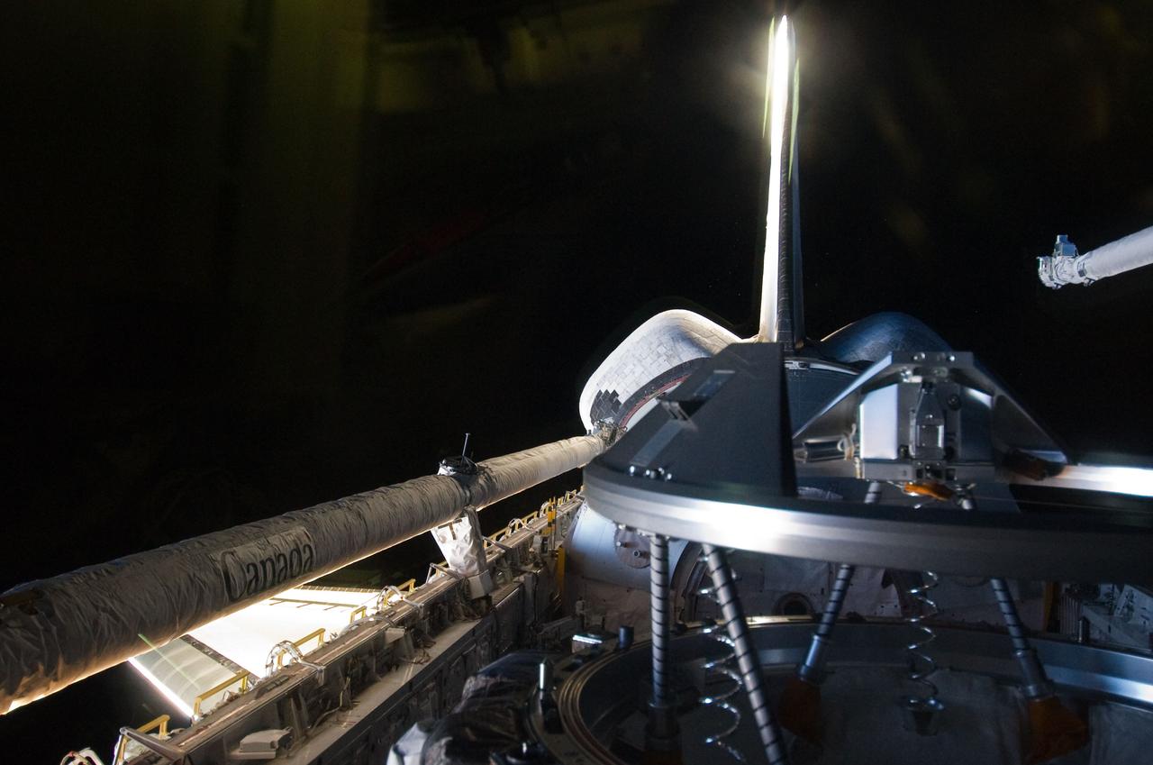 S135-E-007101 (10 July 2011) --- This picture of Atlantis' payload bay, focusing on the docking mechanism, was photographed by one of four STS-135 crewmembers inside the crew cabin.  The orbiter boom sensor system and a portion of the remote manipulator system's robot arm are visible in the frame, exposed during a busy third day in space for the astronauts. The photo was made shortly before the shuttle docked with the International Space Station.  Photo credit: NASA