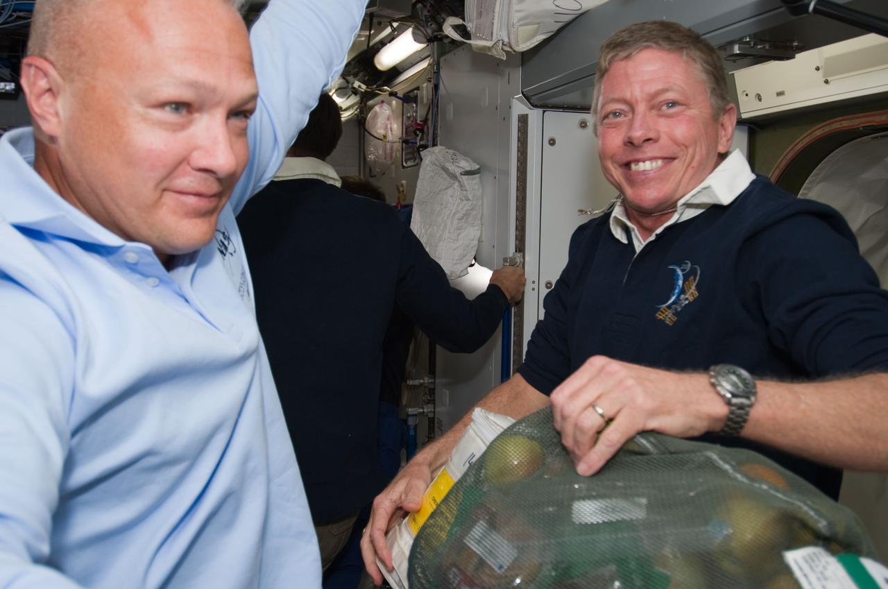 S135-E-007296 (10 July 2011) --- NASA astronauts Doug Hurley (left), STS-135 pilot, and Mike Fossum, Expedition 28 flight engineer, are pictured onboard the International Space Station not long after the docking of the space shuttle Atlantis and the station during the mission’s third day in space. Fossum displays a smile as he holds a bag of fruit and other items which was brought up by the shuttle crew. Photo credit: NASA