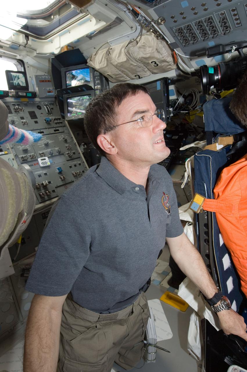 S135-E-007351 (11 July 2011) --- NASA astronaut Rex Walheim, STS-135 mission specialist, watches as astronaut Chris Ferguson (out of frame at right) toggles switches on the overhead panel of the forward flight deck of the space shuttle Atlantis. The action came during the mission's fourth day of activities in Earth orbit and second day while being docked with the International Space Station. Photo credit: NASA