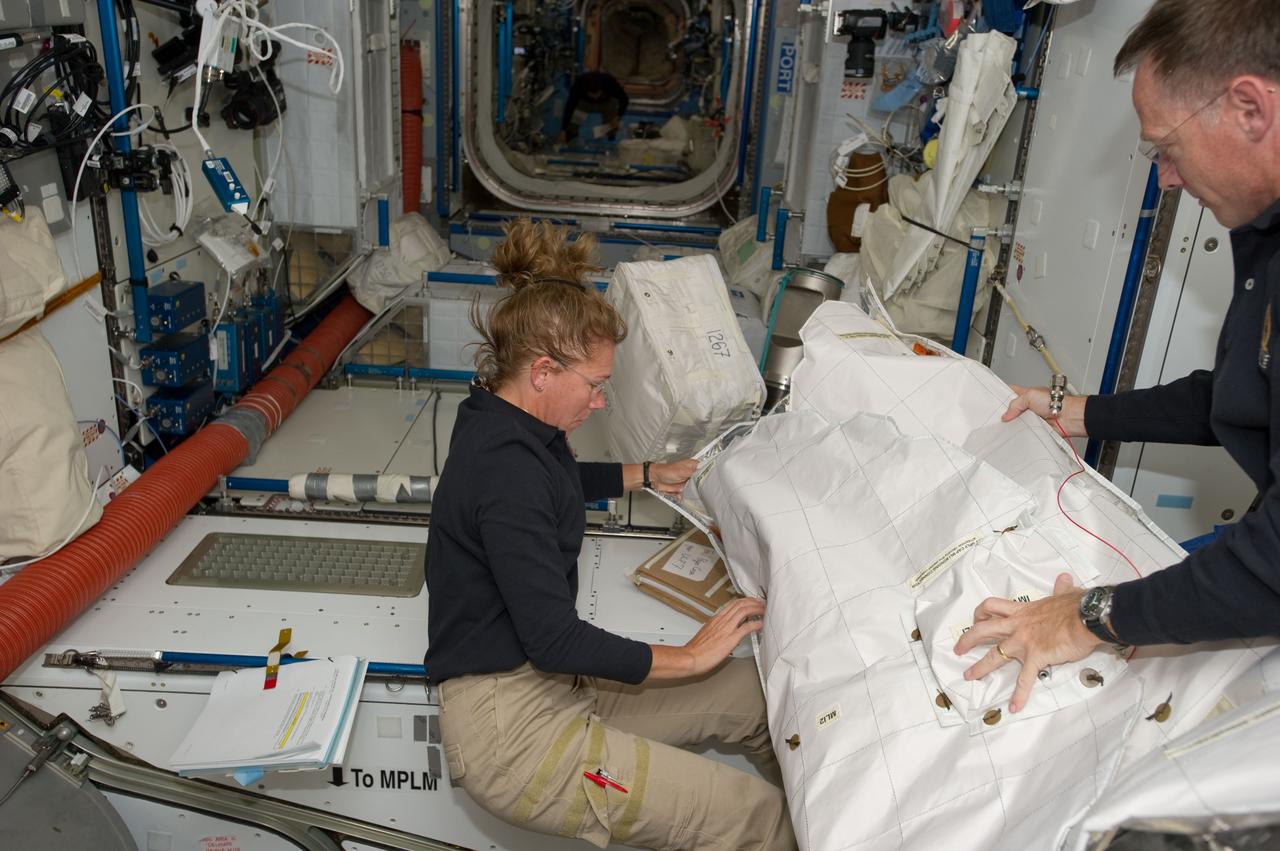 S135-E-007407 (11 July 2011) --- NASA astronauts Sandy Magnus, STS-135 mission specialist, and Chris Ferguson, commander, continue moving supplies and equipment, specifically in Node 2 or Harmony in this scene aboard the International Space Station. The orbital outpost and Atlantis have been docked for more than a day and will remain so for several more. Photo credit: NASA