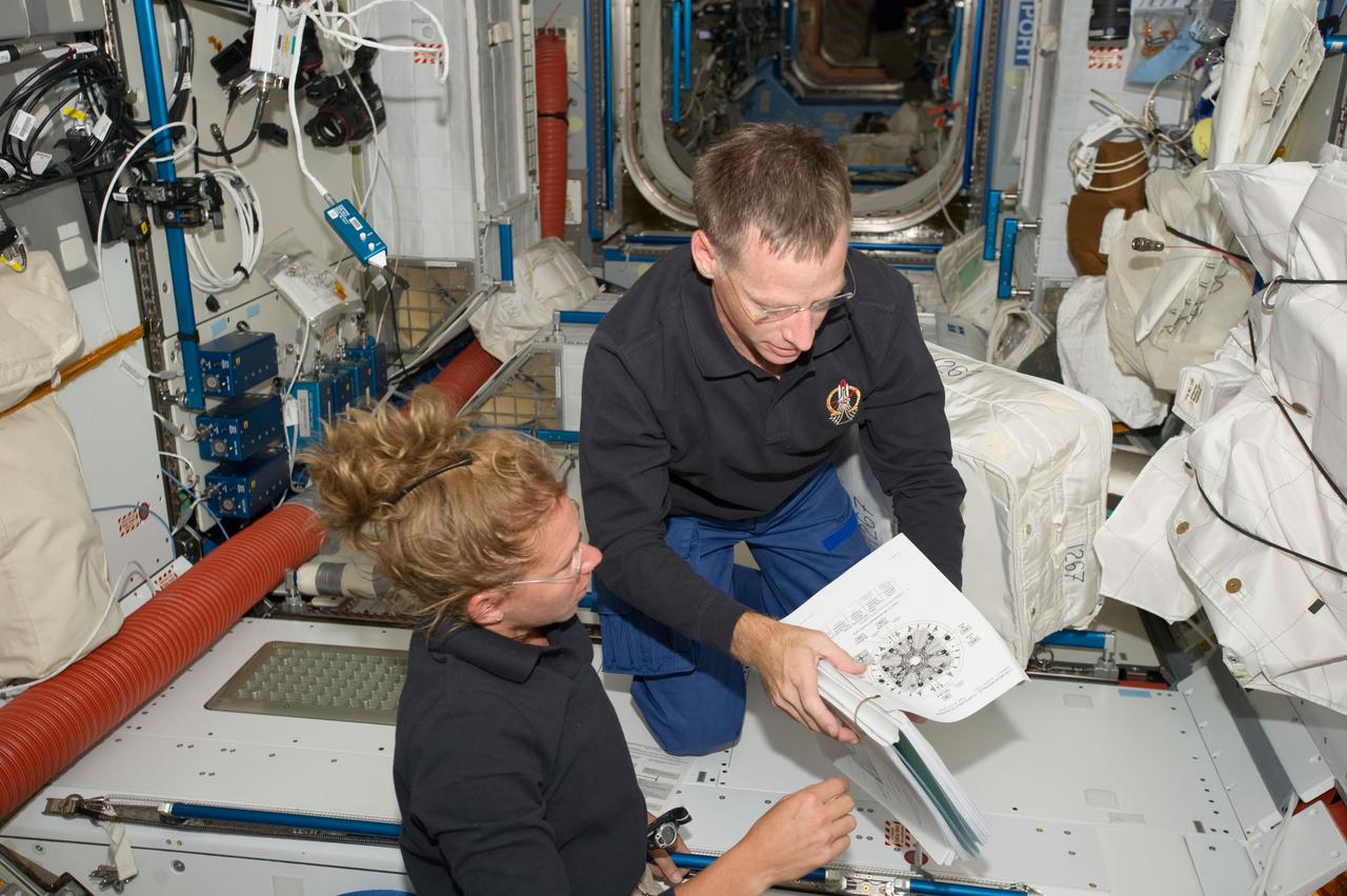 S135-E-007410 (11 July 2011) --- NASA astronauts Sandy Magnus, STS-135 mission specialist, and Chris Ferguson, commander, compare notes in Node 2 or Harmony aboard the International Space Station. The orbital outpost and Atlantis have been docked for more than a day and will remain so for several more. Photo credit: NASA