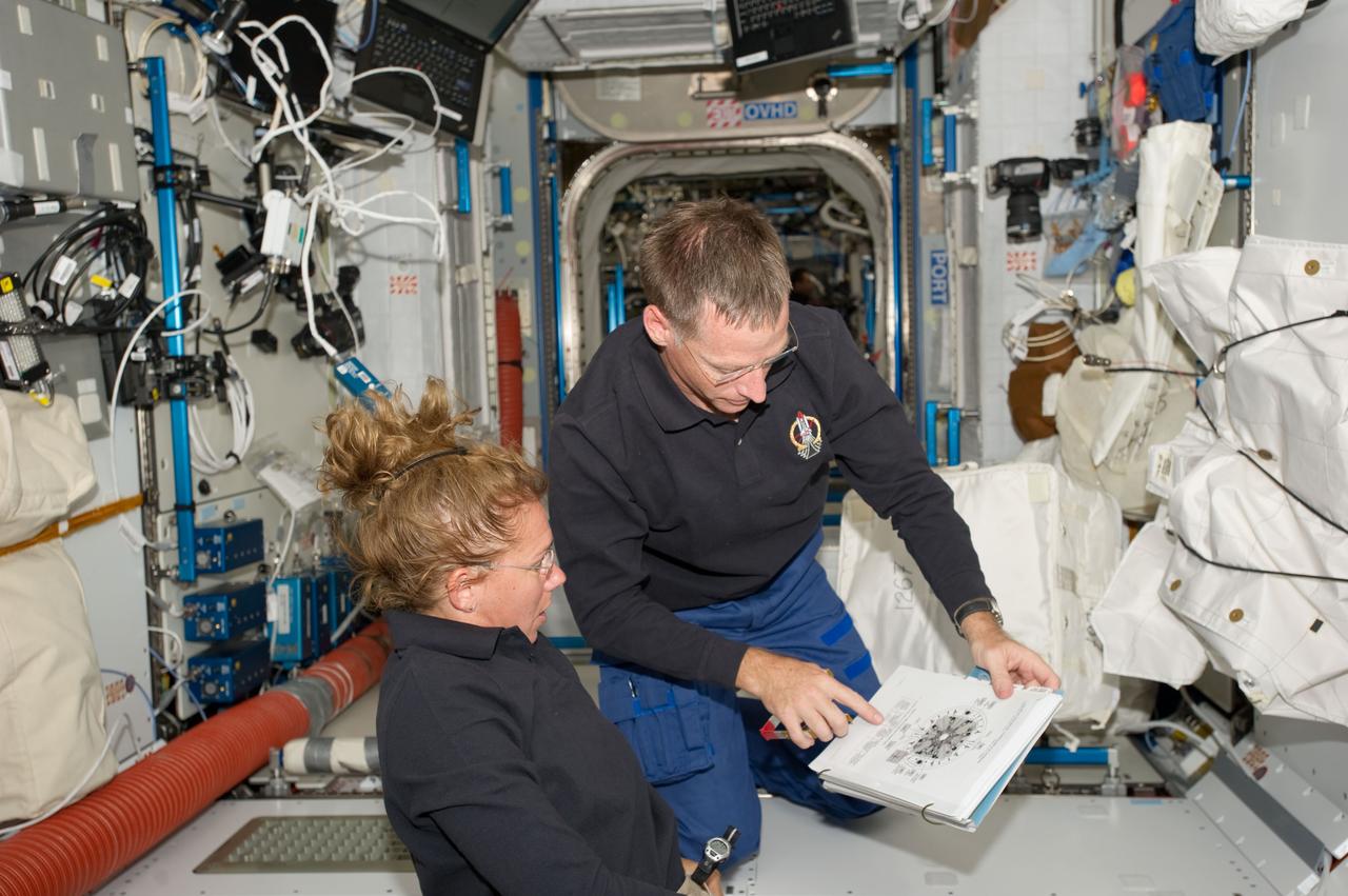 S135-E-007411 (11 July 2011) --- NASA astronauts Sandy Magnus, STS-135 mission specialist, and Chris Ferguson, commander, compare notes in Node 2 or Harmony aboard the International Space Station. The orbital outpost and Atlantis have been docked for more than a day and will remain so for several more. Photo credit: NASA