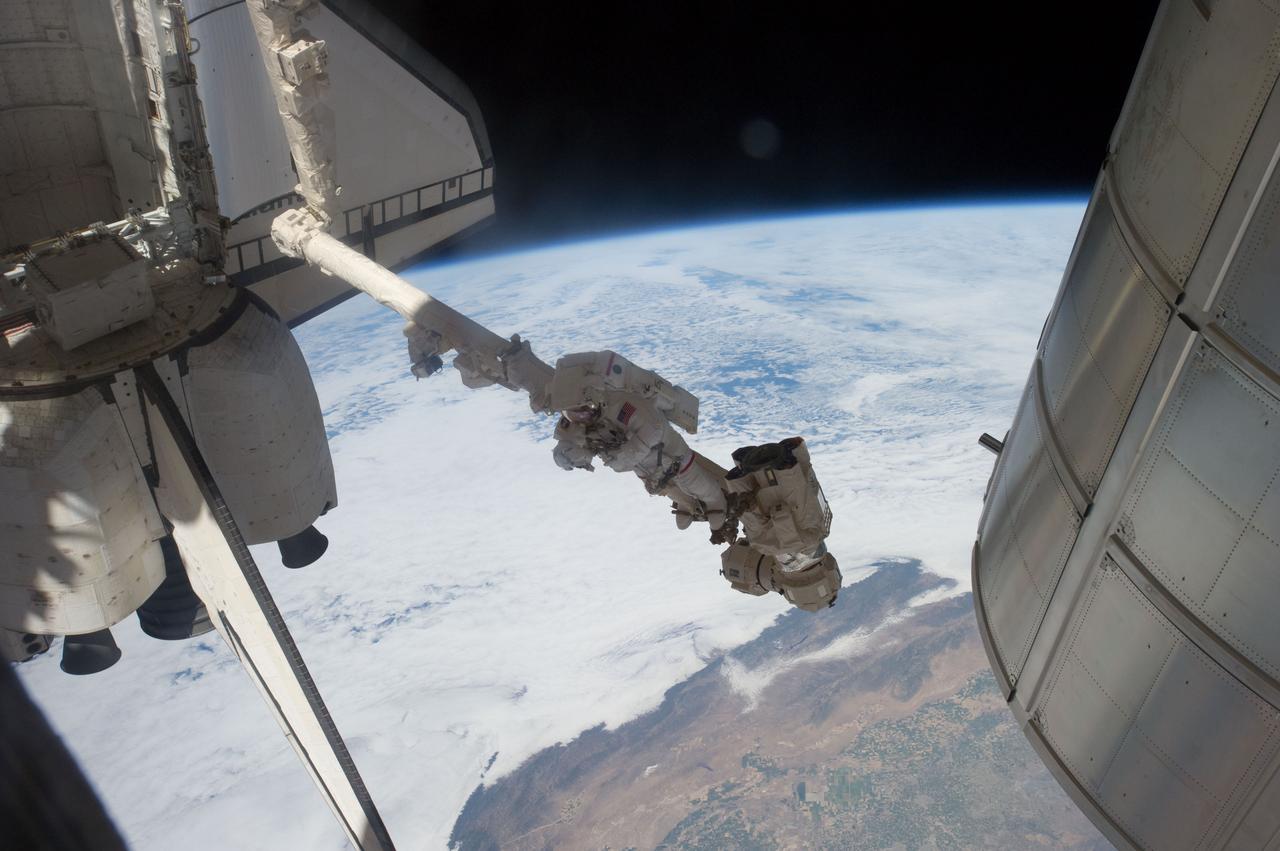 S135-E-007604 (12 July 2011) --- Suspended in a very unique position on the end of the space station remote manipulator system or Canadarm2, NASA astronaut Mike Fossum takes a picture during a July 12 spacewalk. Fossum and NASA astronaut Ron Garan spent just a little over six and a half hours on their various tasks. Photo credit: NASA