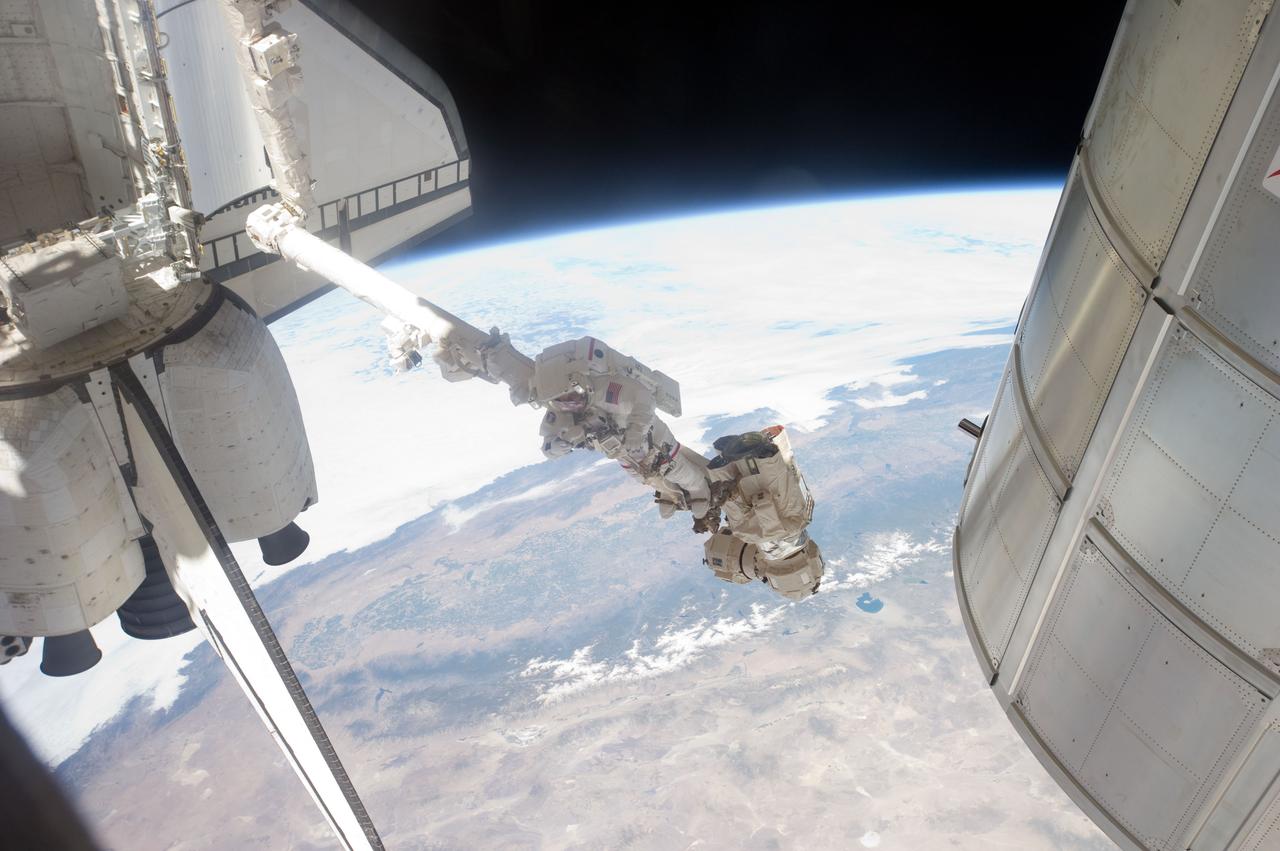 S135-E-007609 (12 July 2011) --- Suspended in a very unique position on the end of the space station remote manipulator system or Canadarm2, NASA astronaut Mike Fossum takes a picture during a July 12 spacewalk. Fossum and NASA astronaut Ron Garan spent just a little over six and a half hours on their various tasks. Photo credit: NASA