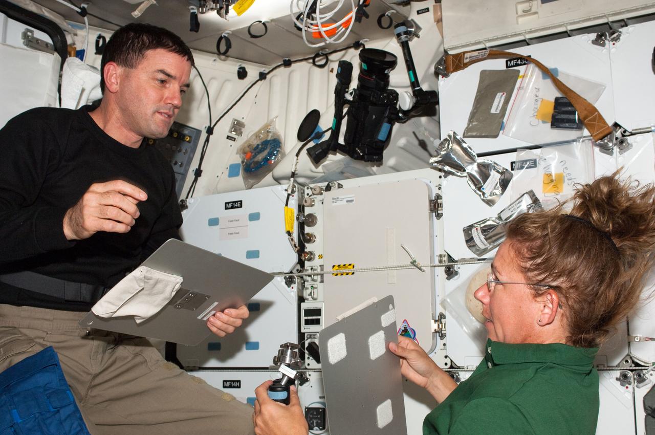 S135-E-007696 (13 July 2011) --- On Atlantis' middeck, NASA astronauts Rex Walheim and Sandy Magnus, STS-135 mission specialists, discuss the large tasks of moving supplies on the joint shuttle/International Space Station complex during the sixth day in space for the four shuttle crewmembers. Photo credit: NASA