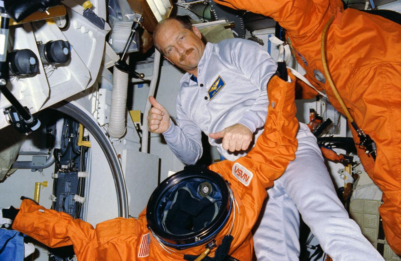 STS026-05-022 (5 Oct  1988) ---  Astronaut Frederick H. (Rick) Hauck, commander, rehearses the donning of the new orange partial pressure suit which he and the other four crewmembers will put on just prior to the entry phase of the flight.  The suit made its debut for the launch phase three days earlier; however the crew had the advantage of a one-G environment for the chore on that occasion.