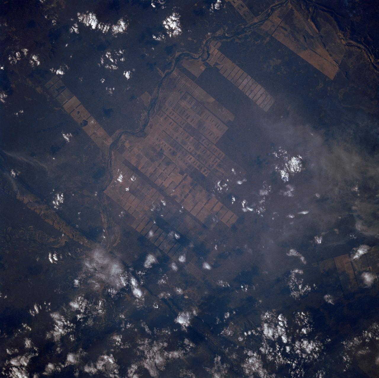 The large field patterns in this view of the Rio Sao Francisco basin, Brazil, South America, (11.5S, 43.5W) indicate a commercial agriculture venture; family subsistence farms are much smaller and laid out in different patterns. Land clearing in Brazil has increased at an alarming rate in recent years and preliminary estimates suggest a 25 to 30% increase in deforestation since 1984. The long term impact on the ecological processes are still unknown.