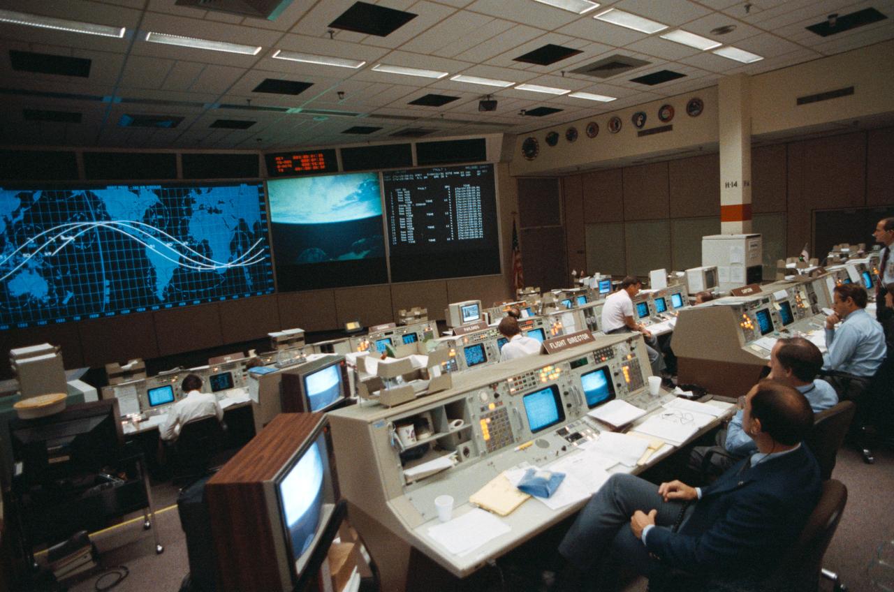 STS026-S-101 (2 Oct 1988) --- Flight controllers in the Johnson Space Center?s mission control center listen to a presentation by the five members of the STS 26 crew on the fourth day of Discovery?s orbital mission.  Flight Directors Charles W. Shaw and James M. (Milt) Heflin (in the foreground) and other controllers view a television image of Earth on a screen in the front of the flight control room while each member relates some inner feelings while paying tribute to the Challenger crew.