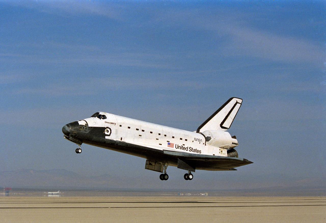 STS-26 Discovery, Orbiter Vehicle (OV) 103, with nose landing gear (NLG) and main landing gear (MLG) deployed glides above dry lakebed runway 17 at Edwards Air Force Base (EAFB), California. This profile view shows OV-103's port side just before MLG touchdown.