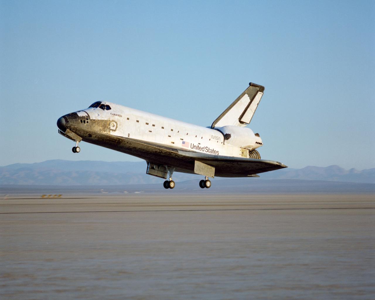 STS-28 Columbia, Orbiter Vehicle (OV) 102, approaches Runway 17 dry lake bed at Edwards Air Force Base (EAFB) California and is photographed just moments before main landing gear (MLG) touchdown. In the distance, are peaks of Southern California mountain range.