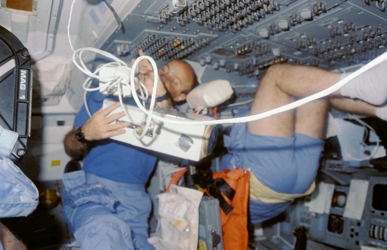STS029-04-032 (13-18 March 1989) --- This scene was a common one during the five-day flight of STS-29. Astronaut John E. Blaha, STS-29 pilot, aims the IMAX camera at Earth through one of Discovery's  overhead windows.  The scene was recorded with a 35mm camera.  The photo was part of the first group of onboard photography from this flight released by NASA on Mar. 19, 1989.