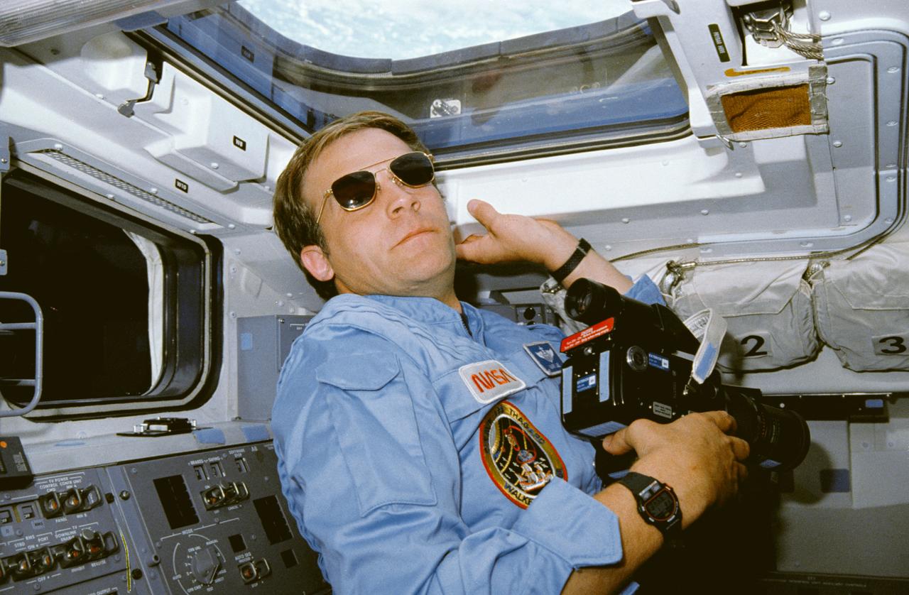 STS030-08-015 (4-8 May 1989) --- Astronaut Mark C. Lee, STS-30 mission specialist, pauses from a of Earth photography on Atlantis' aft flight deck.  He holds a 70mm camera. The scene was recorded with a 35mm camera.  The photo was in a group released by NASA following the completion of a four-day mission in space.