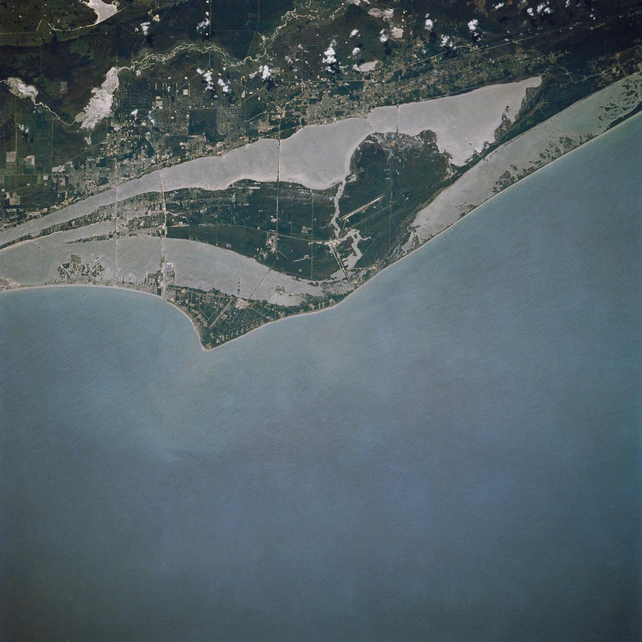 STS030-76-042 (4-8 May 1989) --- For two decades, astronauts have been photographing their launching area from space, but in terms of sharpness and clarity, NASA photo experts feel, few rival this STS-30 vertical scene over the Cape Canaveral area. Sprinkled along the jutting cape feature are a number of launching pads of Kennedy Space Center, and nearby is seen the Shuttle landing facility. Titusville can be seen just above center on the north; Cocoa, Cocoa Beach and Merritt Island are south, near bottom of the frame. St. Johns, Banana and Indian Rivers are easily traced as well.