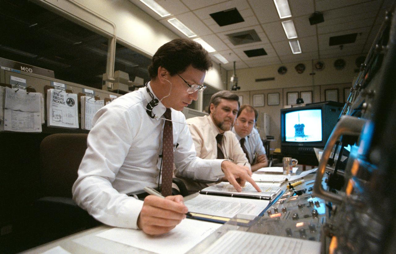 STS030-S-118 (8 May 1989 ) --- The landing phase of the space shuttle Atlantis is monitored by three flight directors in the Flight Control Room (FCR) of the Johnson Space Center's (JSC) Mission Control Center (MCC).  Studying the data at the Flight Director Console are Ronald D. Dittemore, Alan L. (Lee) Briscoe and N. Wayne Hale.  Moments earlier, Atlantis touched down on Runway 22 at Edwards Air Force Bakse (Note monitor).