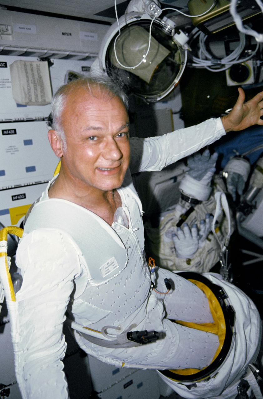 STS-31 Mission Specialist (MS) Bruce McCandless II, wearing liquid cooling and ventilation garment (LCVG), works his way out of the extravehicular mobility unit (EMU) lower torso on the middeck of Discovery, Orbiter Vehicle (OV) 103. McCandless was in a standby mode to perform extravehicular activity (EVA) if needed to support Hubble Space Telescope (HST) deployment and post- deployment tasks. None was needed. His helmet and gloves freefloat in the background.