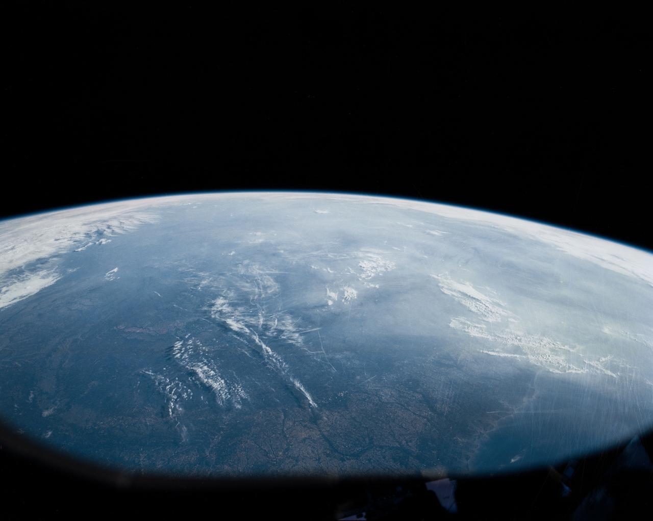 In this oblique view of the Georgia and South Carolina coast, the southern most Appalachians (32.0N, 83.0W) dominate the foreground. Contrails criss cross over Atlanta, a major airline hub. The coastal plain which wraps around the southern Appalachians, is well delineated. Faintly visible under the haze toward Earth's limb are the Great lakes (Lake Michigan near center), the folded belts of the central Appalachians and Long Island, New York.