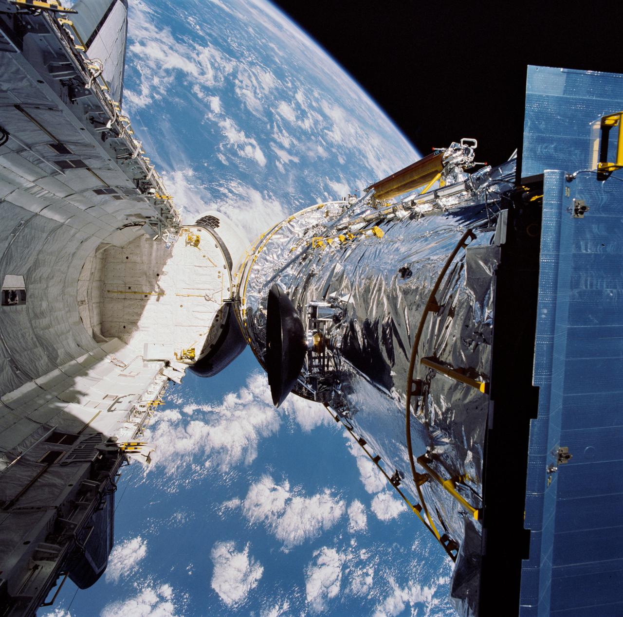 STS031-71-095 (25 April 1990) --- The Hubble Space Telescope (HST) is suspended above Discovery's cargo bay some 332 nautical miles above Earth.  The Canadian-built Remote Manipulator System (RMS) arm, controlled from in-cabin by the astronaut crew members of STS-31, held the huge telescope in this position during pre-deployment procedures, which included extension of solar array panels and antennae.  The photo was made with a 70mm handheld Hasselblad camera.