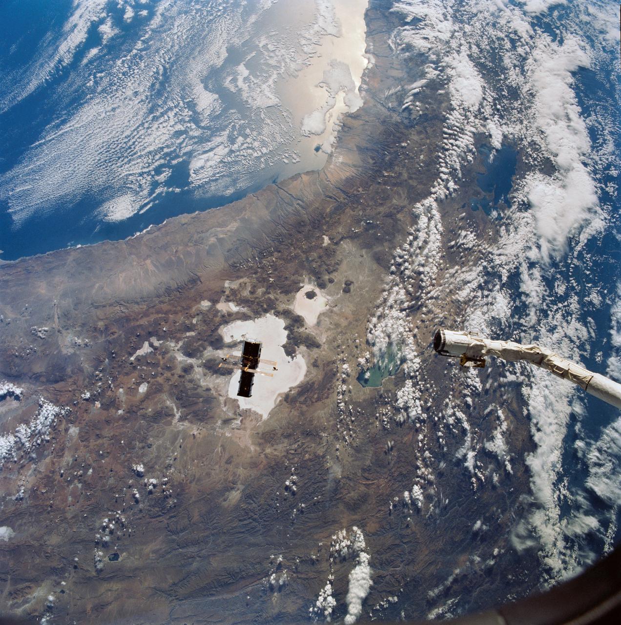 Hubble Space Telescope (HST), with its solar array (SA) wings and high gain antennae (HGA) fully extended,is released from Discovery's, Orbiter Vehicle (OV) 103's, remote manipulator system (RMS) end effector and is set free into Earth orbit by the STS-31 crew. HST drifts away from the end effector over the Andes Mountains.Parts of Bolivia, Peru, Chile, and Argentina are visible. The view covers a huge area of the western half of South America stretching from 14 degrees south latitude to 23 degrees, about 1,000 kilometers.