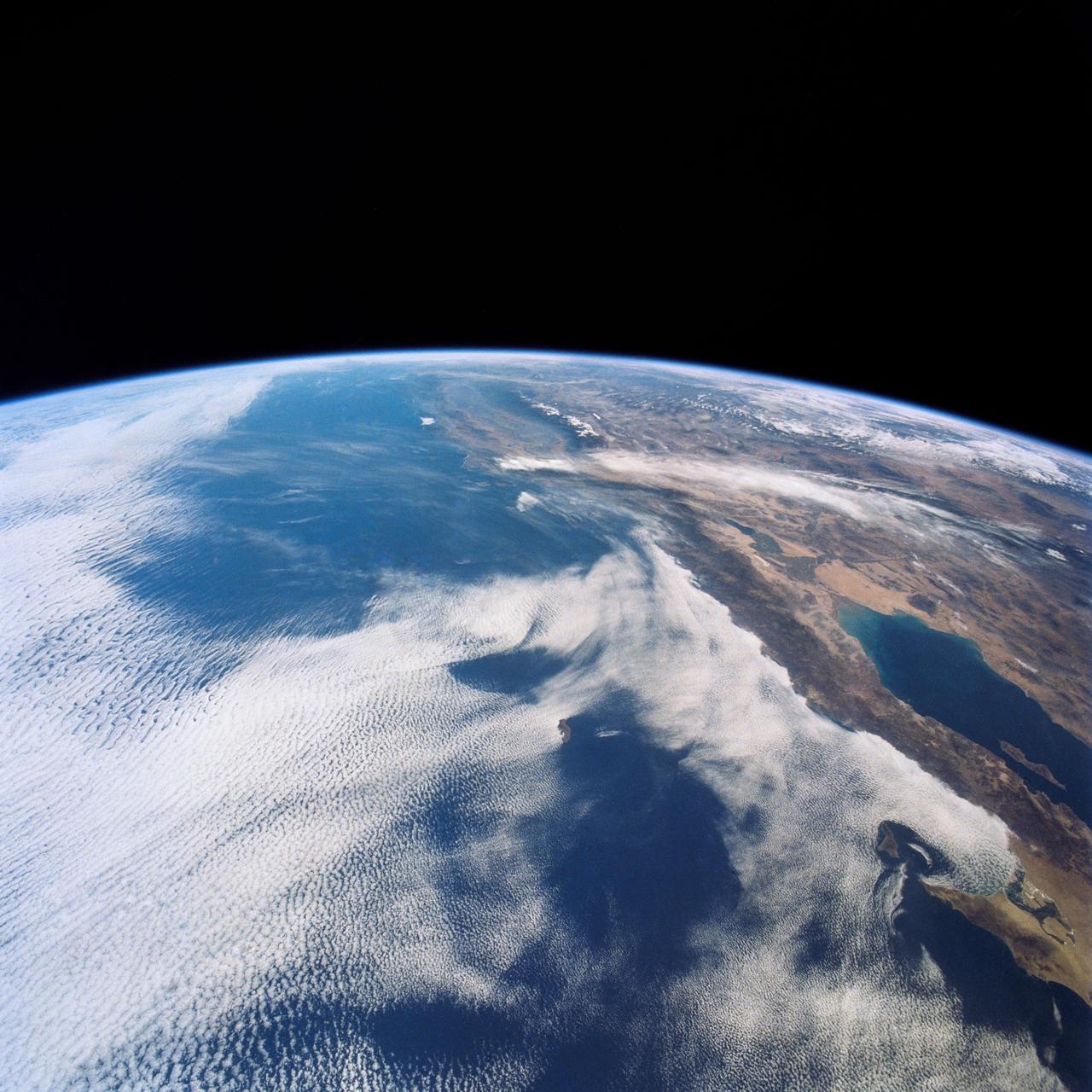 This view shows the west coast of the United States and Mexico (32.5N, 118.0W) and gives an indication of the range of view from orbital altitude. The visual range of this particular scene is from Skammon's Lagoon on Baja to the northern tip of California's Central Valley and Sierra Nevada, a range of over 15 degrees of latitude. Coastal fog drapes over southern California and northern Baja California. White Sands, New Mexico is at far right center.
