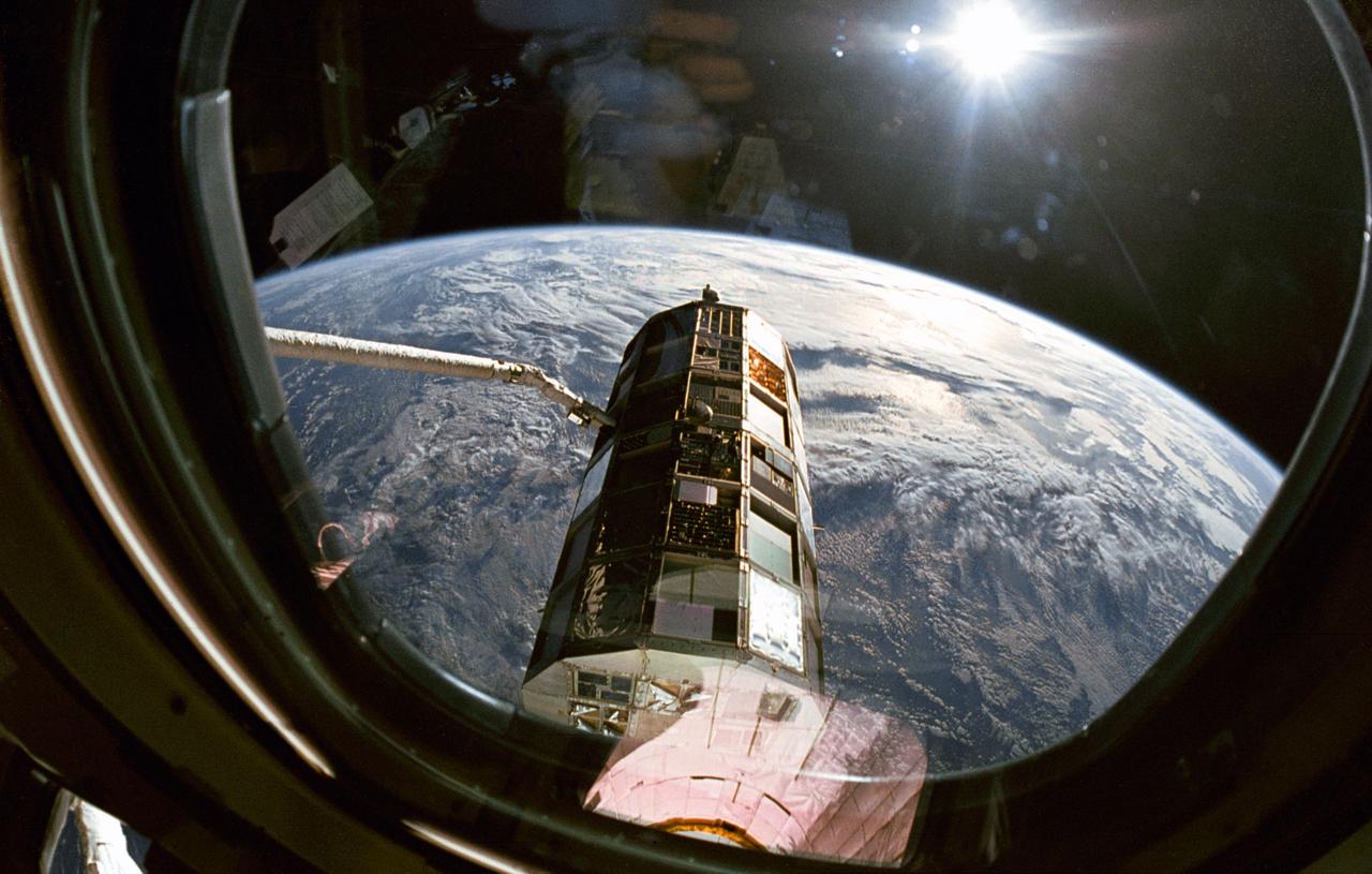 This view taken through overhead window W7 on Columbia's, Orbiter Vehicle (OV) 102's, aft flight deck shows the Long Duration Exposure Facility (LDEF) in the grasp of the remote manipulator system (RMS) during STS-32 retrieval activities. Other cameras at eye level were documenting the bus-sized spacecraft at various angles as the RMS manipulated LDEF for a lengthy photo survey. The glaring celestial body in the upper left is the sun with the Earth's surface visible below.
