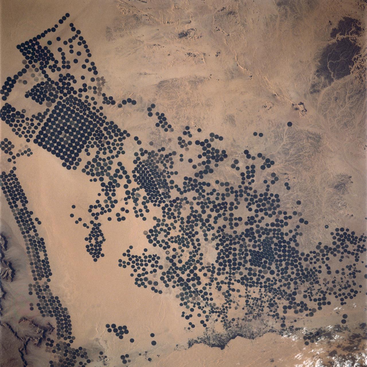 In Saudi Arabia, center-pivot, swing-arm irrigated agriculture complexes such as the one imaged at Jabal Tuwayq (20.5N, 45.0 E) extract deep fossil water reserves to achieve food crop production self sufficiency in this desert environment. The significance of the Saudi expanded irrigated agriculture is that the depletion of this finite water resource is a short term solution to a long term need that will still exist when the water has been extracted.