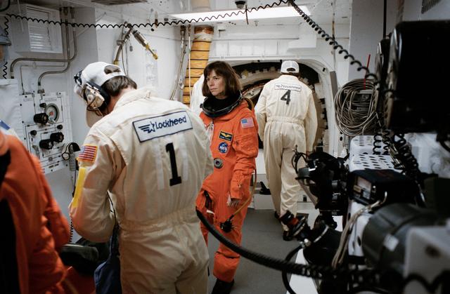 NASA image: STS-32 MS Dunbar looks on as technicians prepare LES equipment in white room