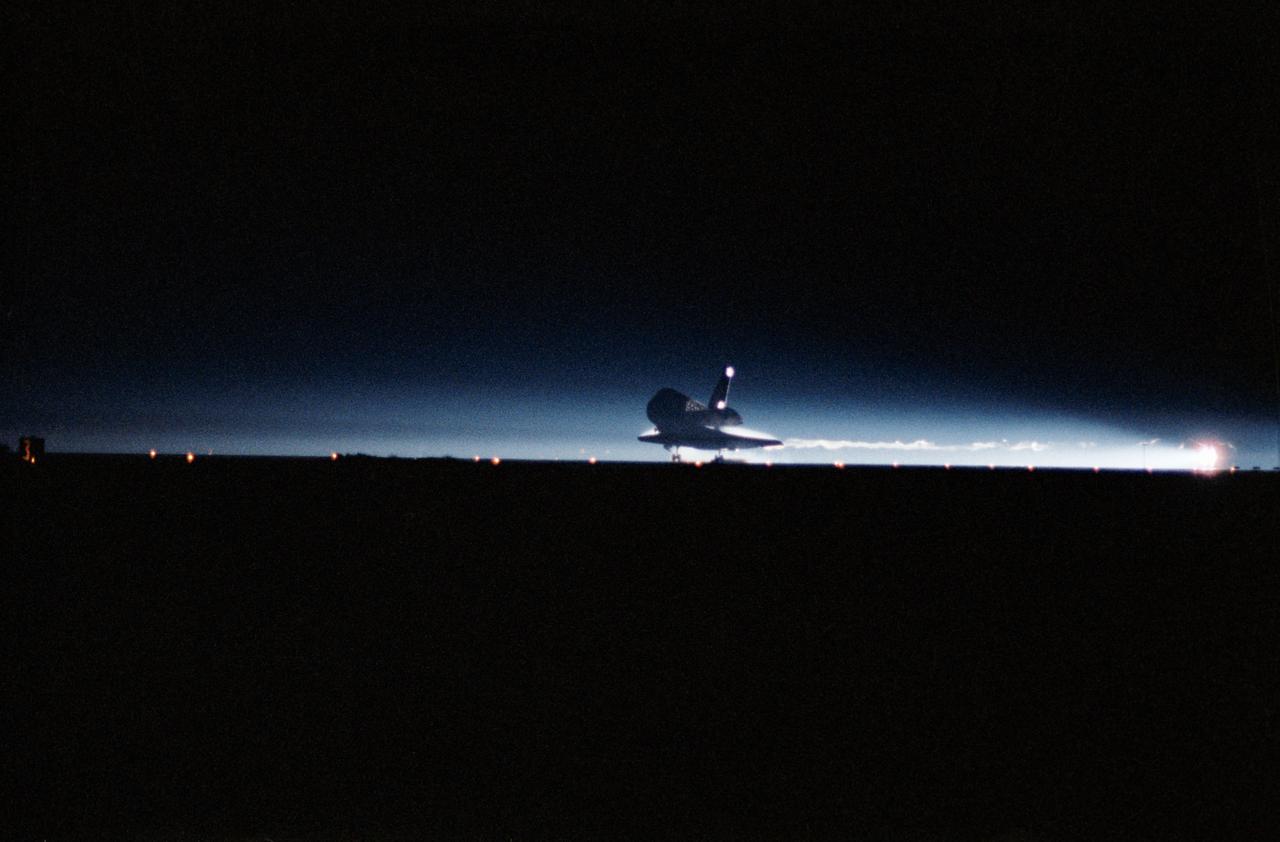 STS-32 Columbia, Orbiter Vehicle (OV) 102, is captured as its main landing gear (MLG) touches down on runway 22 at Edwards Air Force Base (EAFB), California, in the early morning darkness. The night landing ended a record 11-day mission in space. Moments later, at 1:36:38 am Pacific Standard Time (PST), OV-102 came to a complete stop, having logged 4,509,972 miles in flight.
