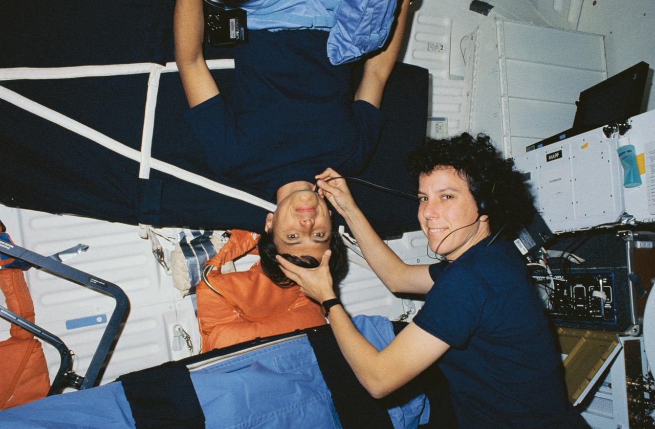 STS034-08-007 (18-23 Oct. 1989) --- Astronaut Ellen S. Baker, an STS-34 mission specialist and medical doctor, conducts a medical examination on astronaut Franklin R. Chang-Diaz, mission specialist, on the middeck of the Earth-orbiting space shuttle Atlantis. Dr. Baker was monitoring Chang-Diaz's blood flow. The scene was recorded on film with a 35mm camera.Photo credit: NASA or National Aeronautics and Space Administration