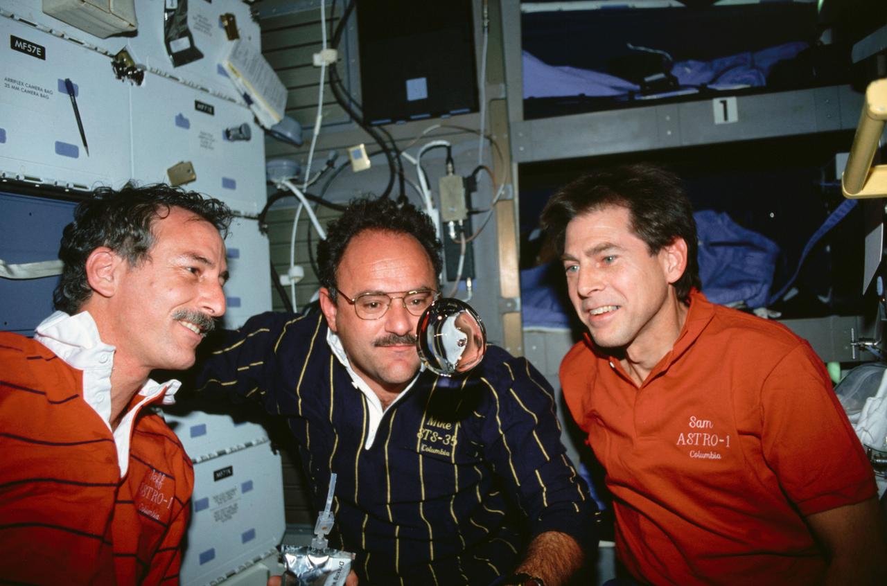 STS035-15-035 (2-10 Dec 1990) --- STS-35 crewmembers perform a microgravity experiment using their drinking water while on the middeck of Columbia, Orbiter Vehicle (OV) 102. Mission Specialist (MS) Jeffrey A. Hoffman (left) has released some water from a drinking container which he holds in his hand. MS John M. Lounge (wearing glasses, center) and Payload Specialist Samuel T. Durrance along with Hoffman study the changing shape and movement of the sphere of water.