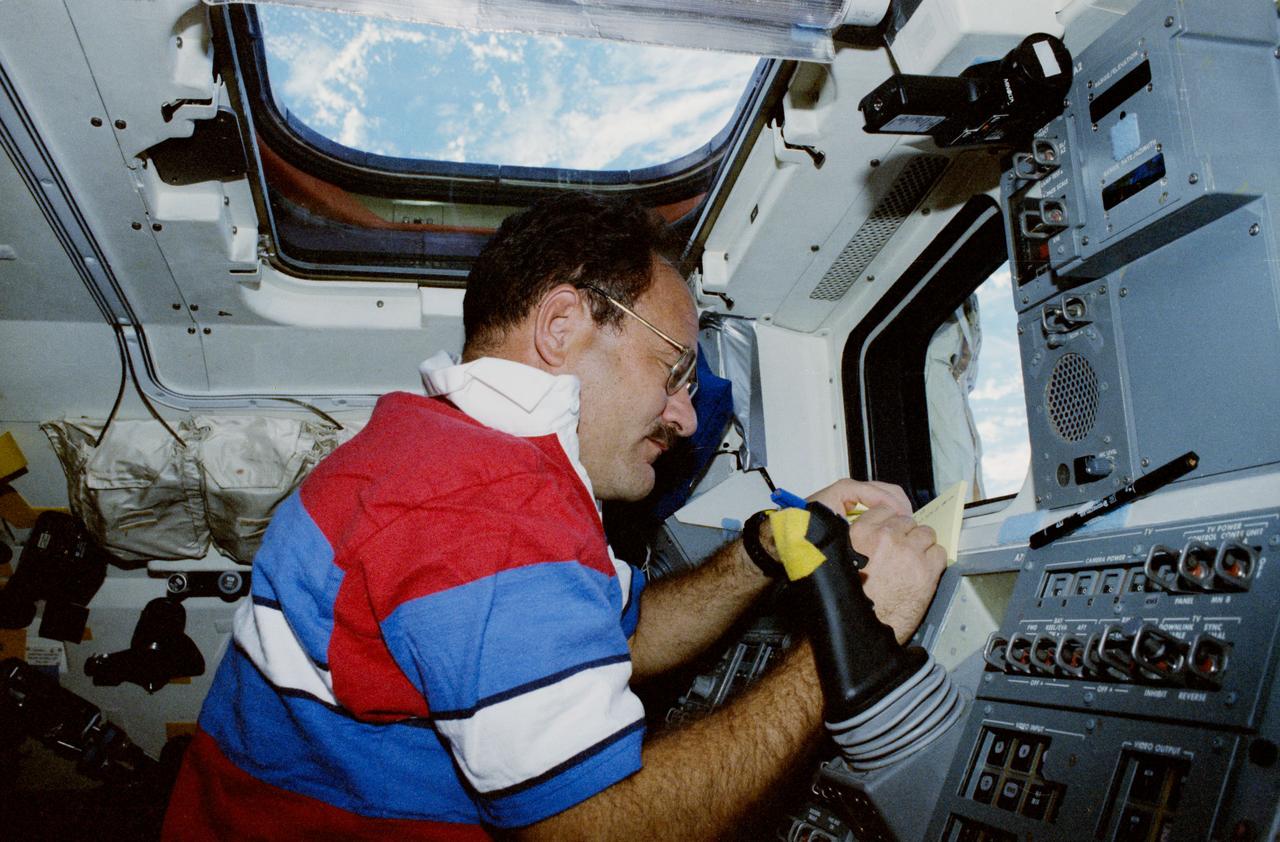 STS035-19-019 (2-11 Dec 1990) --- Astronaut John M. (Mike) Lounge, STS 35 mission specialist makes a notation as he observes telescopes (out of frame) at work in Columbia's cargo bay.  This aft flight deck scene was exposed with a 35mm camera.