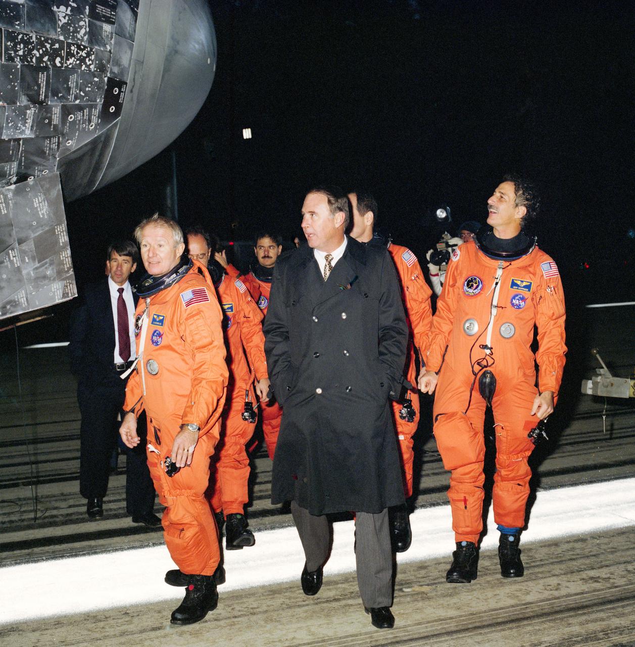 STS035-S-091 (10 Dec 1990) --- Donald R. Puddy (center), Director of Flight Crew Operations at the Johnson Space Center (JSC), joins the STS-35 crewmembers in a post-landing walk-around inspection of the Columbia at Edwards Air Force Base.  Crewmembers pictured are, left to right, Vance D. Brand, John M. (Mike) Lounge, Ronald A. Parise, Guy S. Gardner and Jeffrey A. Hoffman.  Obscured or out of frame are Samuel T. Durrance and Robert A. R. Parker. Dr. William B. Lenoir, NASA Associate Administrator for Space Flight, is at far left background.
