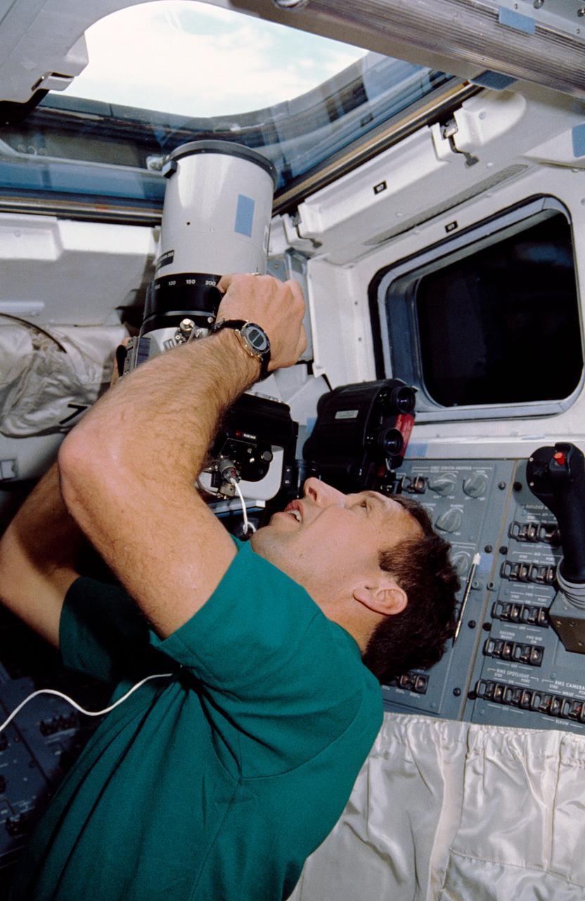 STS-36 Mission Specialist (MS) David C. Hilmers points the large-format AEROLINHOF camera out overhead window W7 on the aft flight deck of Atlantis, Orbiter Vehicle (OV) 104. Hilmers records Earth imagery using the camera. Hilmers and four other astronauts spent four days, 10 hours and 19 minutes aboard OV-104 for the Department of Defense (DOD) devoted mission.