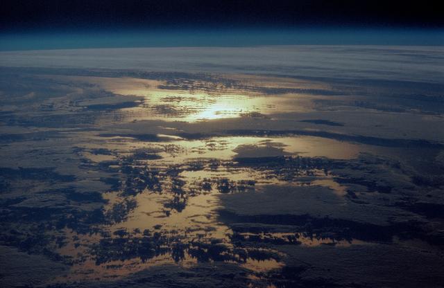 NASA image: STS-36 Earth observation of sun beaming off cloud-covered ocean waters