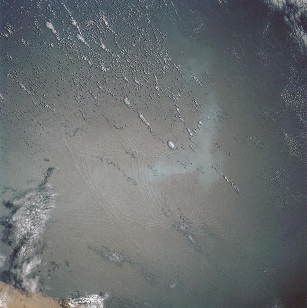 These open ocean Internal Waves were seen off the Namibia Coast, Africa (19.5S, 11.5E). The periodic and regularly spaced sets of incoming internal appear to be diffracting against the coastline and recombining to form a network of interference patterns. They seem to coincide with tidal periods about 12 hours apart and wave length (distance from crest to crest) varies between 1.5 and 5.0 miles and the crest lengths stretch beyond the image.