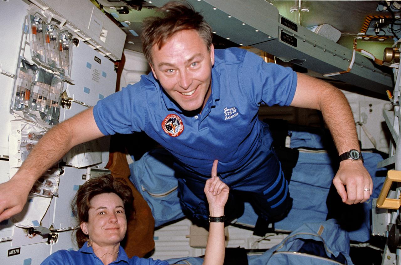 STS037-29-002 (5-11 April 1991) --- Astronauts Linda M. Godwin and Jerry L. Ross perform a balancing act on Atlantis' middeck. With little effort Godwin is able to hold Ross up near the ceiling with her index finger. Although the area the two occupy is very small, a number of articles are seen, including two sleep restraints, the escape pole and Bioserve ITA Materials Dispersion Apparatus bioprocessing test bed (attached to stowage lockers at left). This was one of the visuals used by the STS-37 crewmembers during their April 19 post-flight press conference at the Johnson Space Center (JSC).