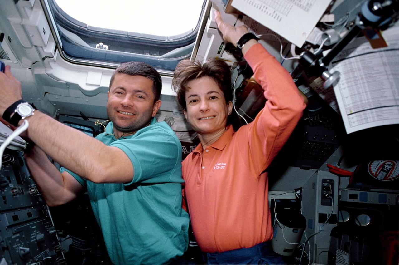 STS037-33-031 (5-11 April 1991) --- Astronauts Kenneth D. Cameron, STS-37 pilot, and Linda M. Godwin, mission specialist, take advantage of a well-lighted crew cabin to pose for an in-space portrait on the Space Shuttle Atlantis' aft flight deck. The two shared duties controlling the Remote Manipulator System (RMS) during operations involving the release of the Gamma Ray Observatory (GRO) and the Extravehicular Activity (EVA) of astronauts Jerry L. Ross and Jerome (Jay) Apt. The overhead window seen here and nearby eye-level windows (out of frame at left) are in a busy location on Shuttle missions, as they are used for payload surveys, Earth observation operations, astronomical studies and other purposes.  Note the temporarily stowed large format still photo camera at lower right corner. This photo was made with a 35mm camera. This was one of the visuals used by the crew members during their April 19 Post Flight Press Conference (PFPC) at the Johnson Space Center (JSC).