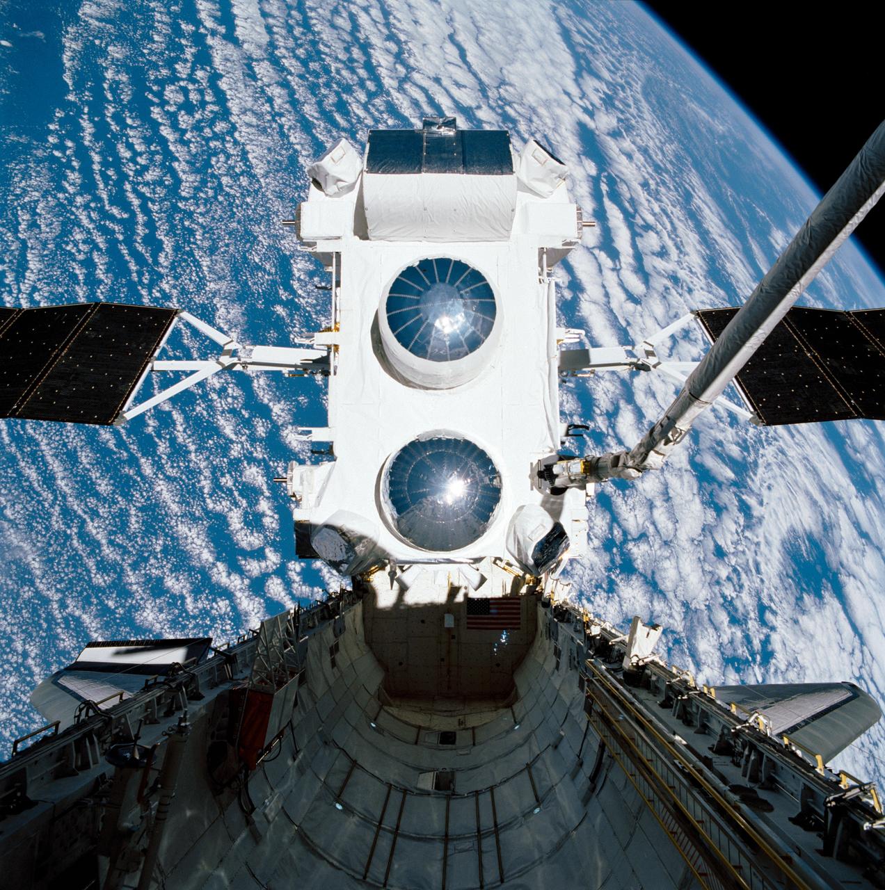 STS037-99-098 (7 April 1991) --- Backdropped against clouds over water, the Gamma Ray Observatory (GRO) is still in the grasp of the Space Shuttle Atlantis' Remote Manipulator System (RMS) in this 70mm scene.  A special Extravehicular Activity (EVA) was required by astronauts Jerry L. Ross and Jerome (Jay) Apt to manually extend the high-gain antenna on GRO.  The five-member crew capped off a busy Flight Day 3 by releasing the heavy payload.