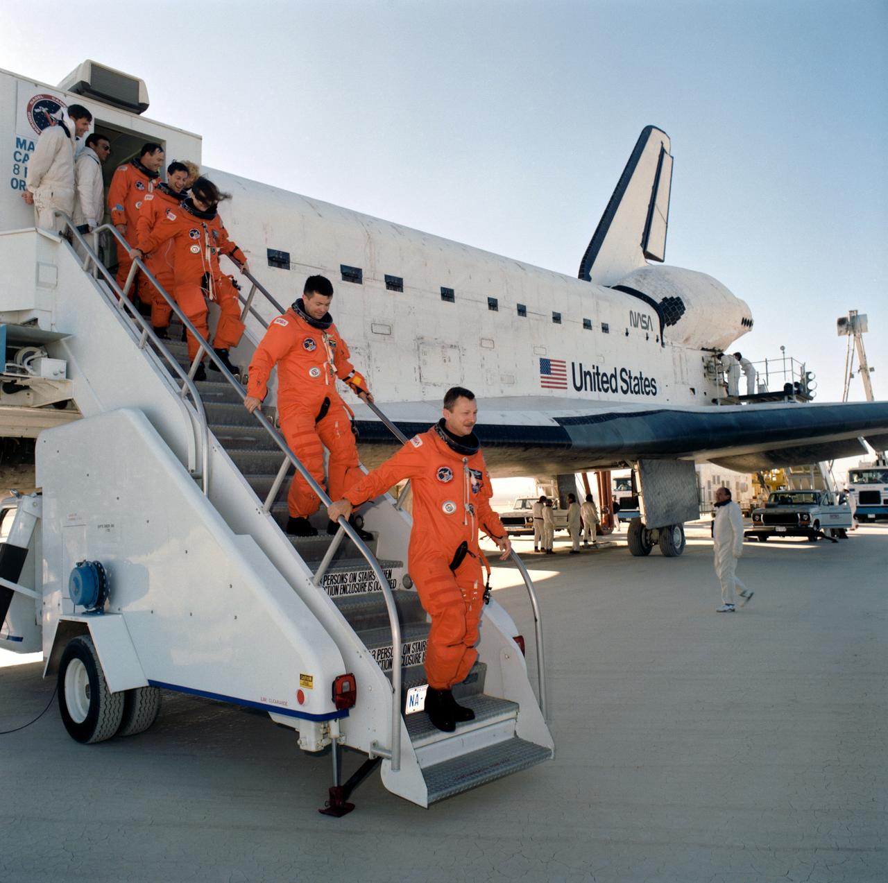 STS037-S-087 (11 April 1991) --- STS-37 crewmembers egress Atlantis via mobile stairway after landing on runway 33 dry lake bed at Edwards Air Force Base. Leading the  crewmembers down the stairway is mission commander Steven R. Nagel. He is followed by pilot Kenneth D. Cameron, Mission Specialists Linda M. Godwin, Jerome Apt and Jerry L. Ross.