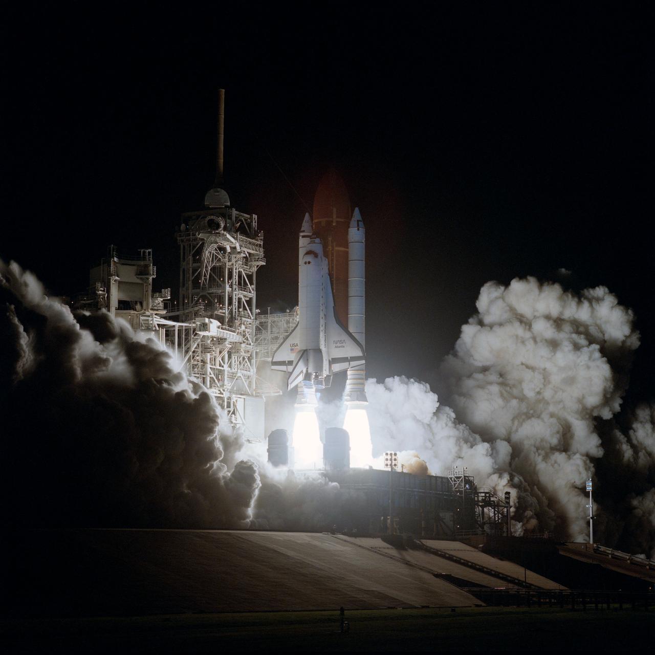 STS-38 Atlantis, Orbiter Vehicle (OV) 104, lifts off from Kennedy Space Center (KSC) Launch Complex Pad at 6:46:15:0639 pm (Eastern Standard Time (EST)). As OV-104, atop the external tank (ET) and flanked by two solid rocket boosters (SRBs), rises above the mobile launcher platform, exhaust smoke fills the area surrounding the launch pad. SRB and space shuttle main engine (SSME) firings glow against the night darkness and light up the fixed service structure (FSS) and retracted rotating service structure (RSS). STS-38 is a Department of Defense (DOD) devoted mission.
