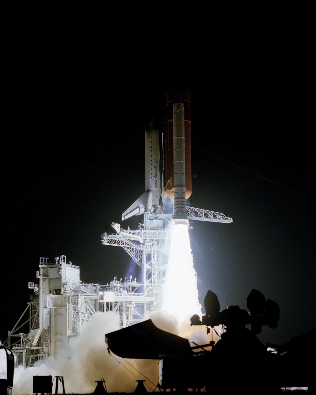 STS-38 Atlantis, Orbiter Vehicle (OV) 104, lifts off from Kennedy Space Center (KSC) Launch Complex (LC) Pad at 6:48:15:0639 pm (Eastern Standard Time (EST)) for Department of Defense (DOD)-devoted mission. OV-104, atop the external tank (ET) and flanked by solid rocket boosters (SRBs), is almost clear of the launch tower which is lit up by the SRB and space shuttle main engine (SSME) firings. Spotlight equipment is silhouetted against the SRB/SSME glow in the foreground. The retracted rotating service structure (RSS) is highlighted against the evening darkness by the launch fireworks.
