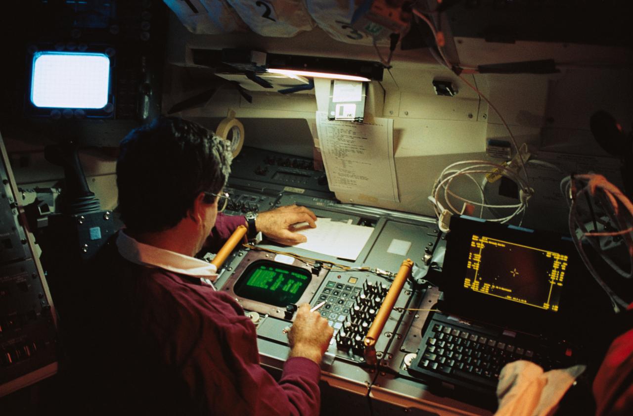 STS039-09-036 (28 April-6 May 1991) ---  Astronaut Charles L. (Lacy) Veach monitors experiment data on the aft flight deck of the Earth-orbiting Discovery.  The photograph was taken with a 35mm camera.  Veach and six other NASA astronauts spent over eight days in space busily collecting data for this mission, dedicated to the Department of Defense.